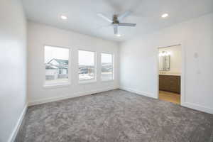 Unfurnished bedroom with light colored carpet, ceiling fan, and ensuite bathroom