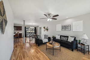 Living room featuring ceiling fan, a textured ceiling, and light wood-type flooring