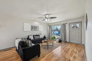 Living room featuring ceiling fan, light hardwood / wood-style floors, and a textured ceiling