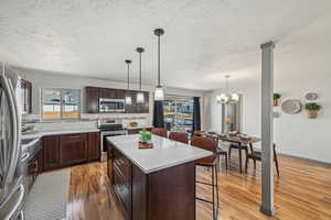 Kitchen featuring appliances with stainless steel finishes, a breakfast bar, decorative backsplash, hanging light fixtures, and a center island