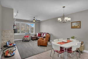 Interior space featuring light parquet flooring, rail lighting, and ceiling fan with notable chandelier