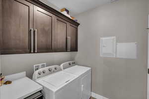 Laundry area featuring cabinets, washing machine and dryer, electric panel, and a textured ceiling