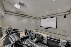 Home theater room with crown molding and carpet floors