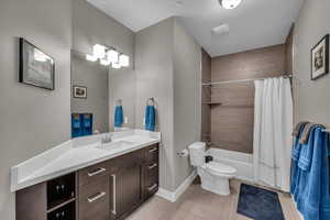 Full bathroom with vanity, toilet, a textured ceiling, and shower / bath combo