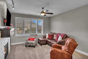 Living room featuring a stone fireplace and ceiling fan