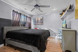 Bedroom featuring ceiling fan, light hardwood / wood-style flooring, and a textured ceiling