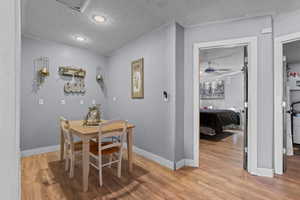 Dining space with ceiling fan, light wood-type flooring, and a textured ceiling