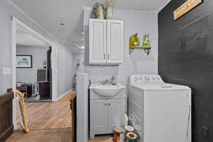 Clothes washing area with light tile patterned flooring, sink, cabinets, a textured ceiling, and washer / clothes dryer