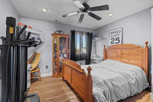 Bedroom with a textured ceiling, ceiling fan, and light hardwood / wood-style flooring