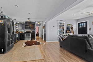 Kitchen with tasteful backsplash, ceiling fan, black appliances, a textured ceiling, and light hardwood / wood-style flooring