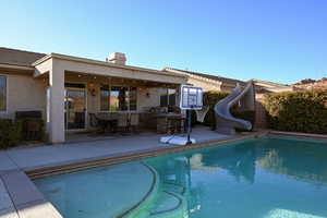 View of pool featuring area for grilling, a patio, and a water slide