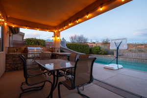 View of patio / terrace with outdoor dining space, an outdoor kitchen, a fenced backyard, and a fenced in pool