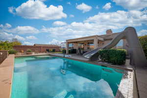 View of pool with a fenced in pool, fence, a water slide, and a patio