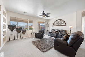 Living room with ceiling fan, carpet, and a textured ceiling