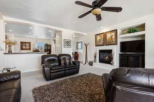 Carpeted living room with ceiling fan, built in features, and a textured ceiling