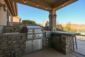 View of patio with exterior kitchen, a grill, and sink