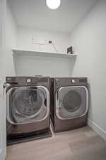 Washroom with separate washer and dryer and light hardwood / wood-style flooring