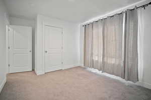 Unfurnished bedroom with light colored carpet and a closet