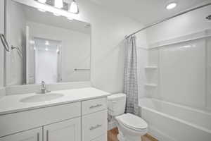 Full bathroom with hardwood / wood-style flooring, vanity, toilet, and shower / bath combination with curtain