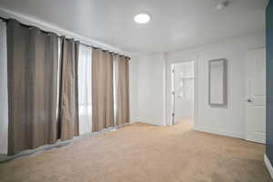 Empty room featuring plenty of natural light and light colored carpet