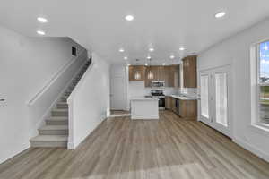 Kitchen featuring sink, light hardwood / wood-style flooring, a kitchen island, pendant lighting, and stainless steel appliances