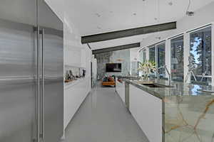 Kitchen featuring sink, stainless steel appliances, white cabinets, quartzite countertops, and decorative light fixtures