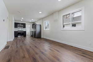 Unfurnished living room with dark hardwood / wood-style floors and a healthy amount of sunlight