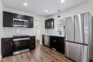 Kitchen featuring sink, decorative light fixtures, hardwood / wood-style floors, and appliances with stainless steel finishes