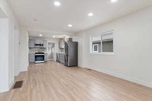 Kitchen featuring stainless steel appliances, gray cabinets, backsplash, and light hardwood / wood-style floors