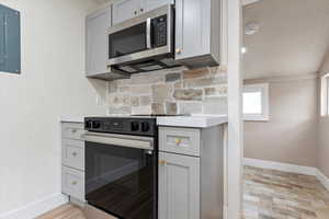 Kitchen featuring gray cabinetry, electric range, and electric panel