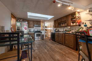 Kitchen with dark hardwood / wood-style flooring, stainless steel appliances, and a textured ceiling