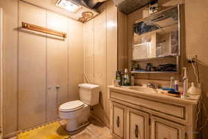 Bathroom featuring tile patterned floors, wood walls, vanity, and toilet