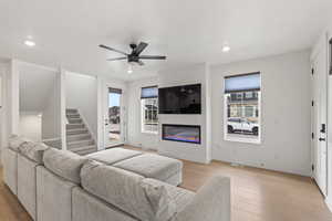 Living room with ceiling fan and light hardwood floors and gas fireplace