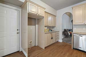 Kitchen with light brown cabinetry, a textured ceiling, wood-type flooring, and dishwasher