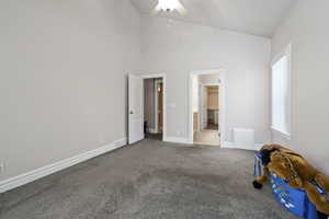 Unfurnished bedroom with light carpet and high vaulted ceiling