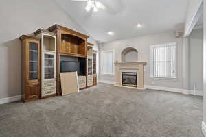 Unfurnished living room with a fireplace, high vaulted ceiling, ceiling fan, and carpet flooring