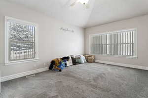 Interior space with vaulted ceiling, ceiling fan, and a textured ceiling