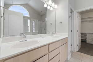 Bathroom featuring tile patterned flooring, an enclosed shower, vanity, and lofted ceiling