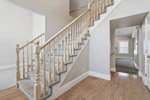 Staircase with hardwood / wood-style flooring and a towering ceiling