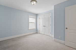 Unfurnished bedroom with a closet, light carpet, and a textured ceiling