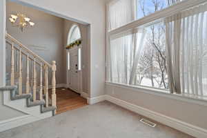 Foyer entrance with carpet floors and an inviting chandelier