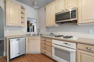 Kitchen featuring sink, stainless steel appliances, light hardwood / wood-style floors, a textured ceiling, and light brown cabinetry