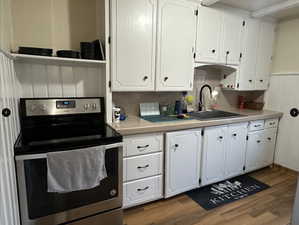 Kitchen with sink, white cabinetry, stainless steel range with electric stovetop, dark hardwood / wood-style flooring, and tile counters