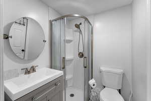 Bathroom featuring vanity, toilet, and an enclosed shower