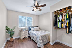 Bedroom featuring dark wood-type flooring, ceiling fan, and a closet