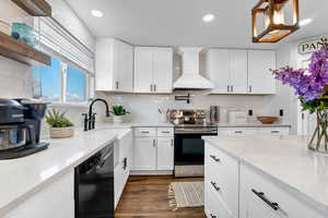 Kitchen with stainless steel electric range oven, premium range hood, pendant lighting, white cabinetry, and black dishwasher