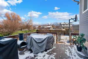 Snow covered patio with area for grilling and a deck with mountain view