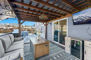 Snow covered patio with wine cooler, a mountain view, and an outdoor hangout area