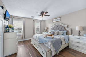 Bedroom with a textured ceiling, dark wood-type flooring, and ceiling fan