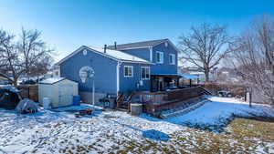 Snow covered rear of property with central AC and a storage unit